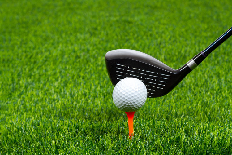 Close-up of golf club and ball on grassy land