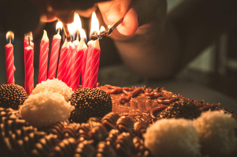 Cropped hand burning candles on birthday cake