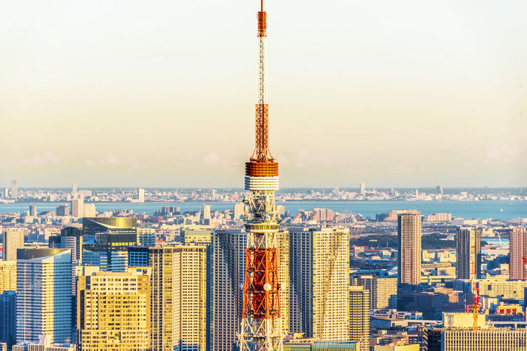 Communications tower amidst cityscape against clear sky