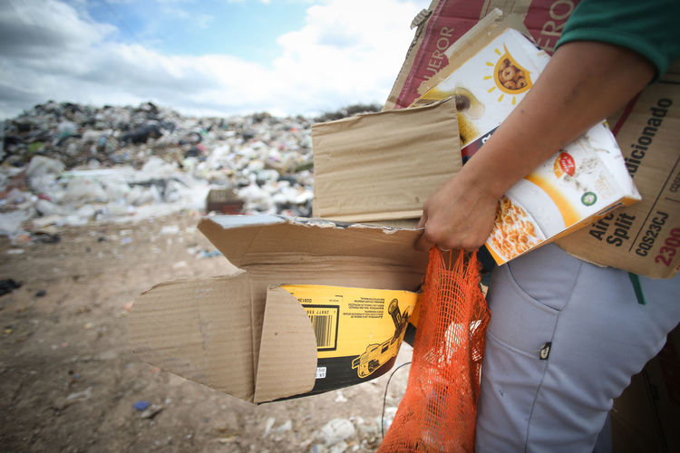 Midsection of man holding garbage against sky