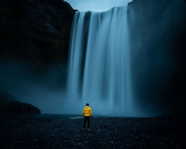 Rear view of man looking at waterfall