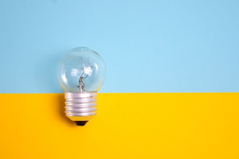 Close-up of yellow light bulb on table against wall