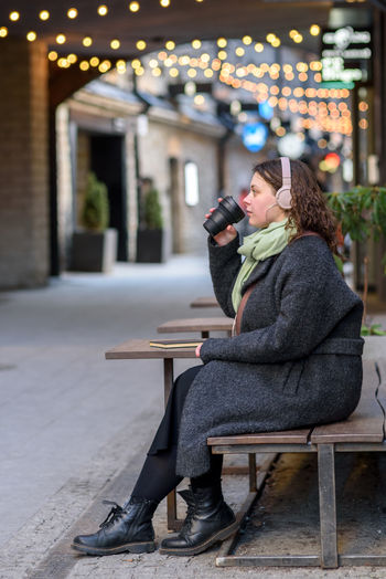 Young woman using mobile phone while sitting on street