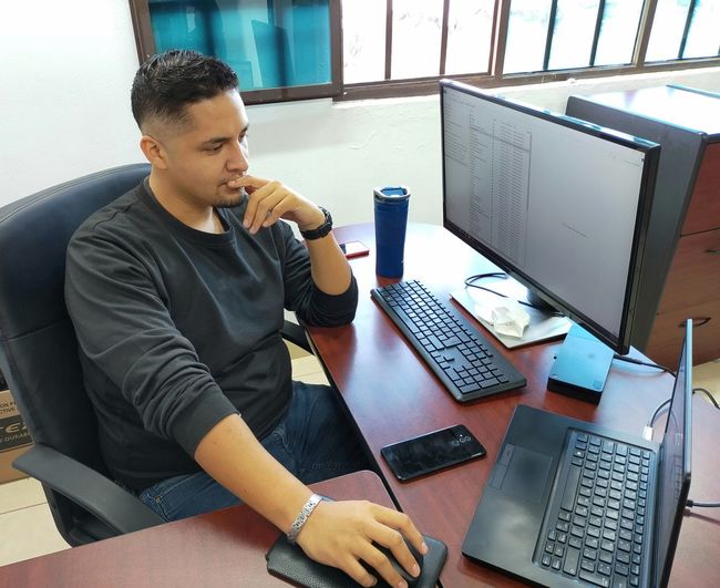 Latino businessman, working in his office thinking about making decisions, using mobile phone.