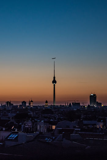 Silhouette buildings in city against sky at sunset