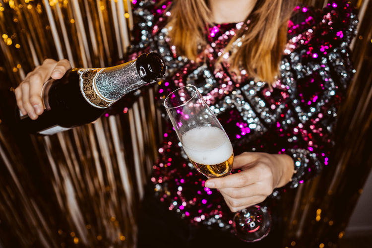 Midsection of woman pouring champagne in glass
