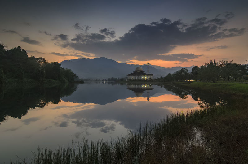 Darul quran mosque and lake against dramatic cloudy sky during sunrise