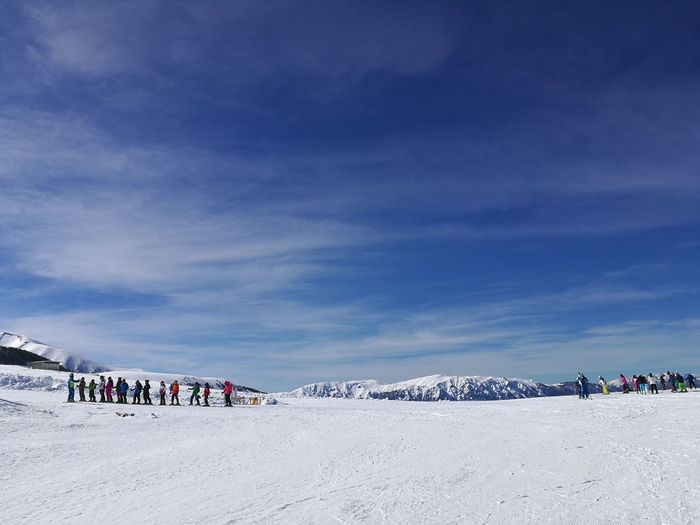 People on snow covered landscape against sky