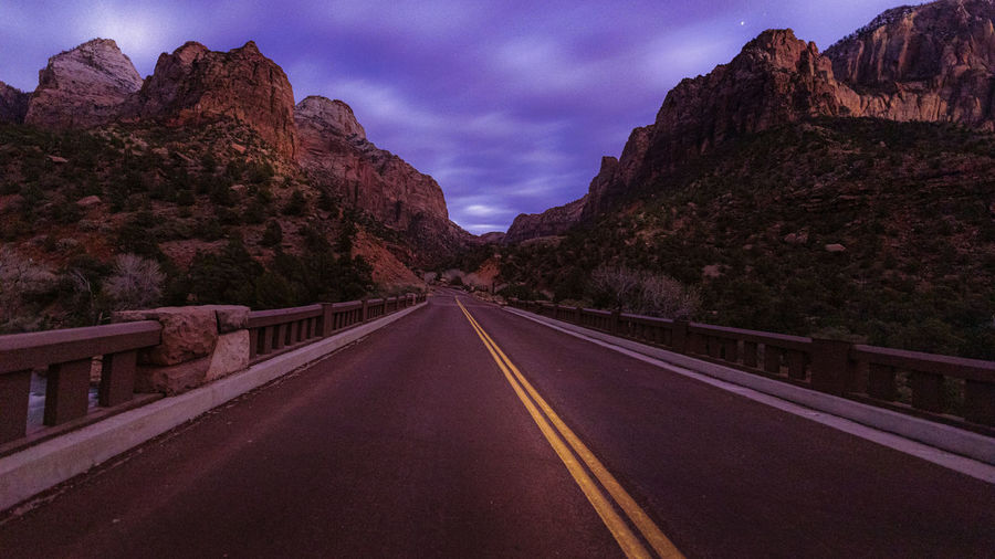 Road leading towards mountains against sky