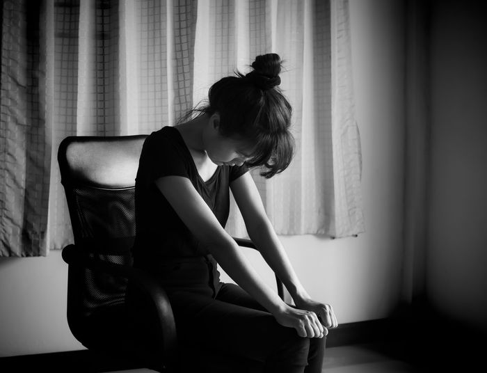 Portrait woman sitting in chair. she looking mobile and cry. black and white images. 