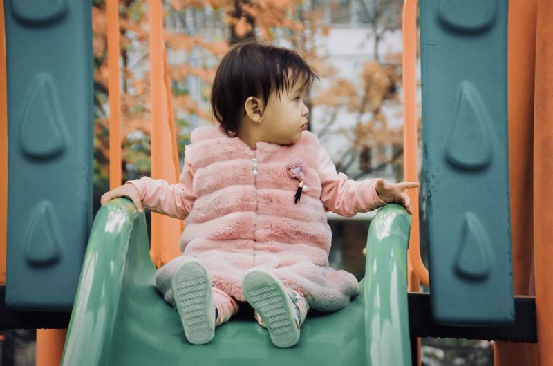 Full length of cute girl sitting on slide
