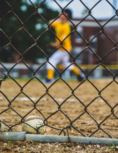 Close-up of baseball seen through chainlink fence