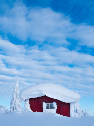 White house on snow covered landscape against sky
