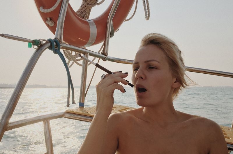 Young woman smoking on boat in sea during sunset