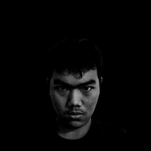 Portrait of young man against black background