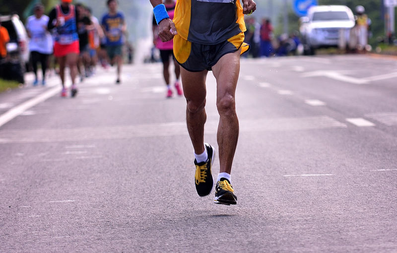 Low section of man running on road during marathon