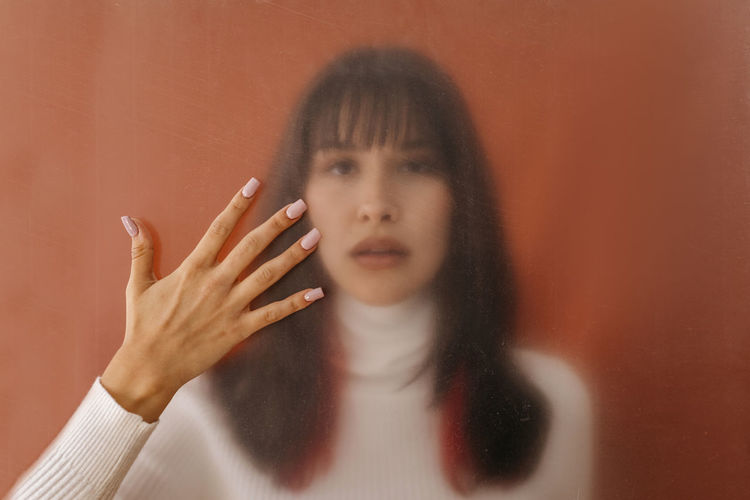 Hand touching plastic sheet with woman in background