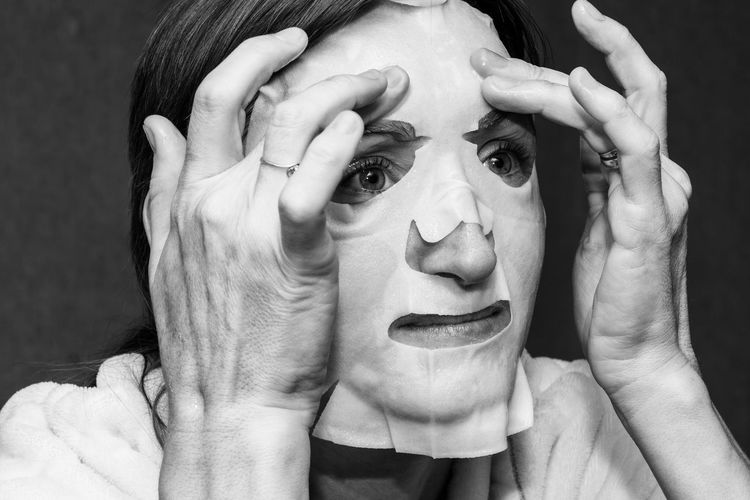 A young woman puts a white moisturising mask on her face
