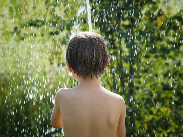 Boy under shower in garden