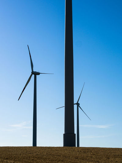 Low angle view of windmill on field against clear blue sky
