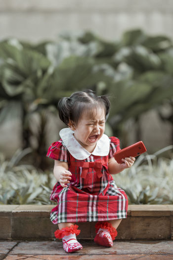 Full length of cute baby girl sitting on footpath