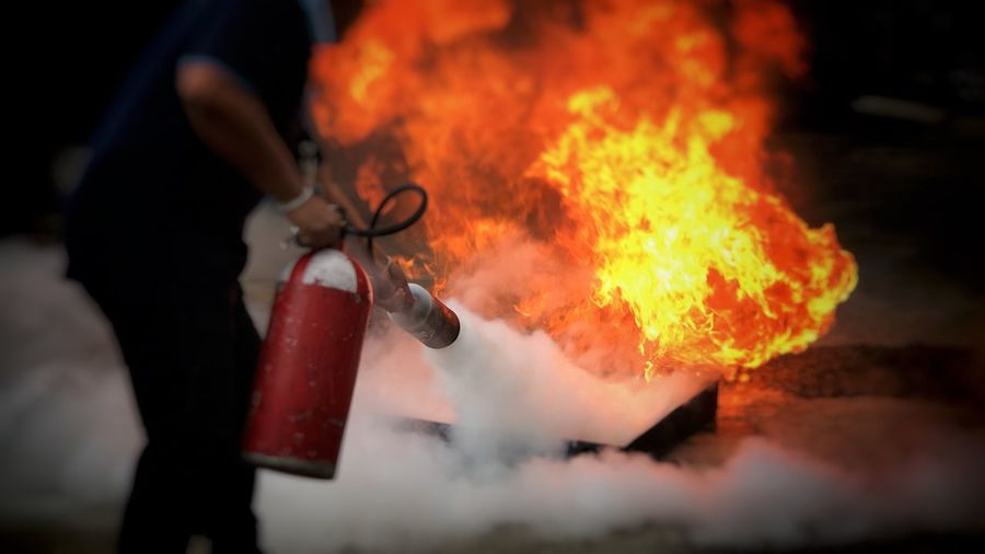 Midsection of man using fire extinguisher