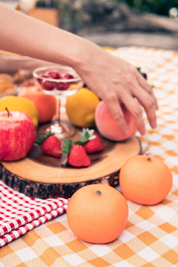 Close-up of hand holding orange fruits on cutting board