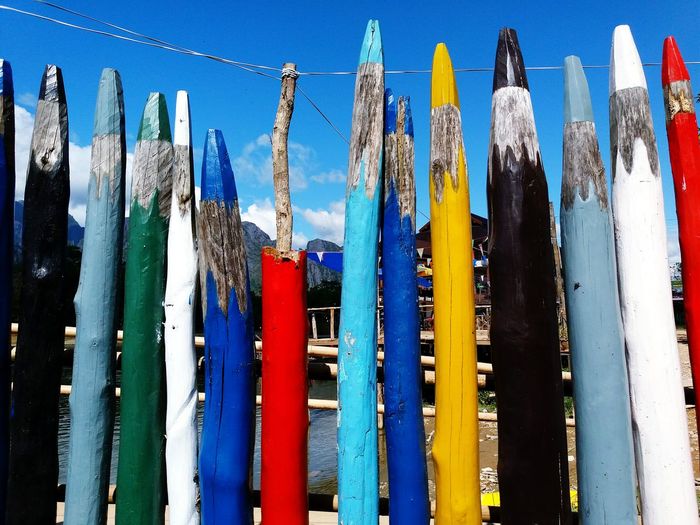 Close-up of multi colored wooden posts against lake
