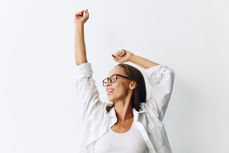 Young woman with arms raised against white background