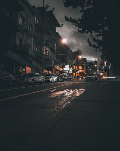 Cars on street by buildings in city at night