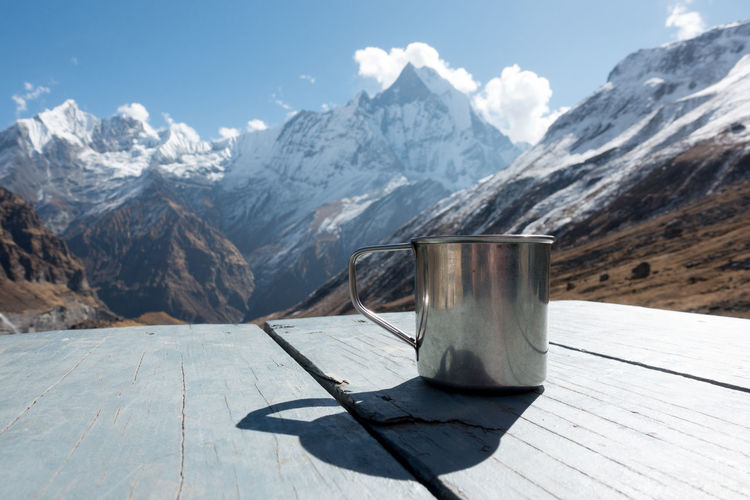Close-up of mug on table against mountain range
