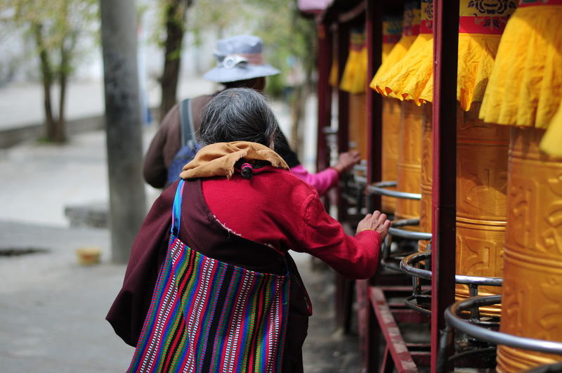 Rear view of people walking by prayer wheels at temple