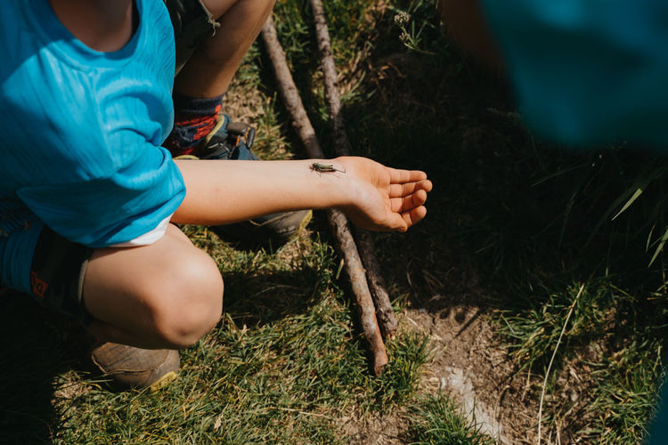 Midsection of woman sitting on field in forest