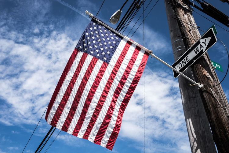 Low angle view of american flag against cloudy blue sky