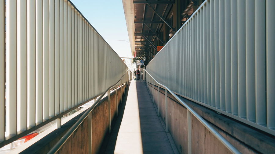 Walkway amidst railing during sunny day