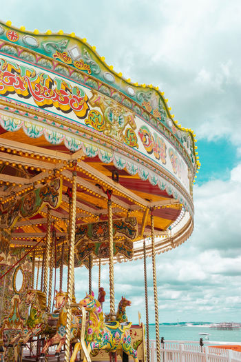 Low angle view of carousel against cloudy sky