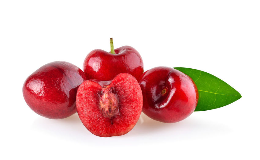Close-up of red cherries over white background