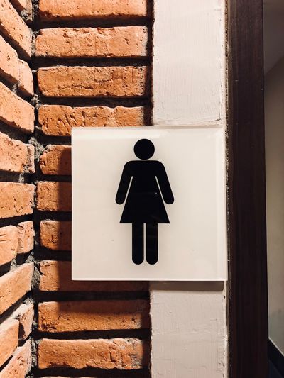 Woman restroom sign on wall background 