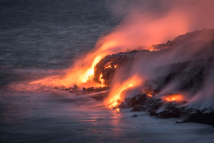 Majestic volcanic landscape with lava flowing into sea