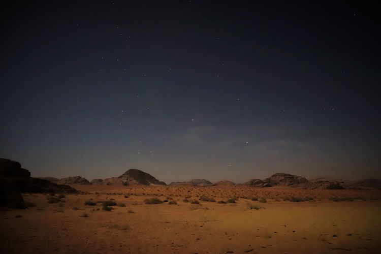 View of barren landscape with mountains at night