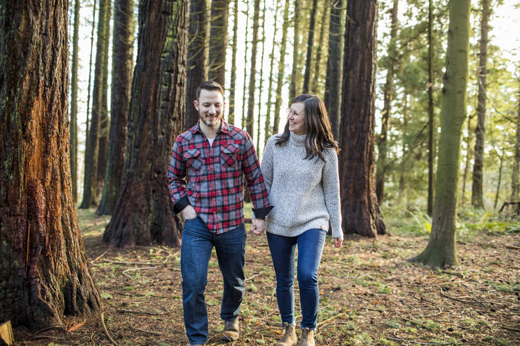 Relaxed couple walking through forest in evening light.