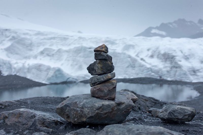 Stack of rocks against lake during winter