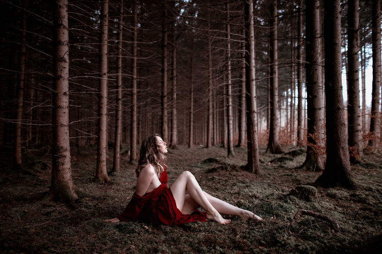 Full length of woman sitting in forest