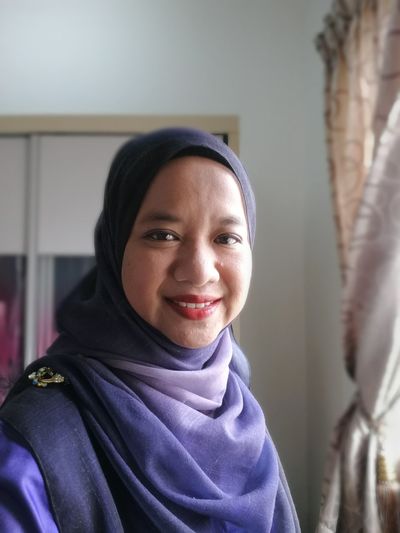 Portrait of smiling woman in hijab at home