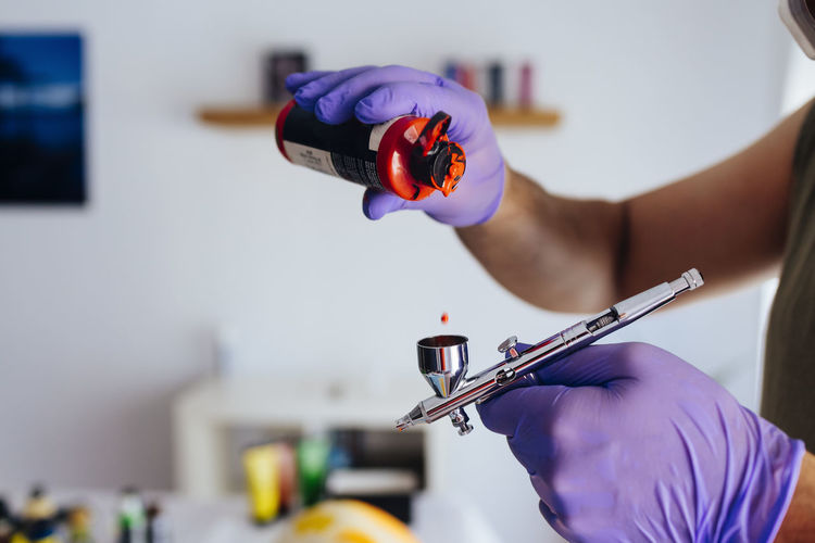 Close up of painter's hands recharging his airbrush.