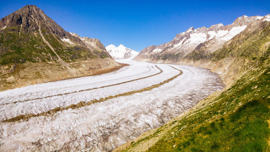 Panoramic view of road amidst mountains against clear blue sky