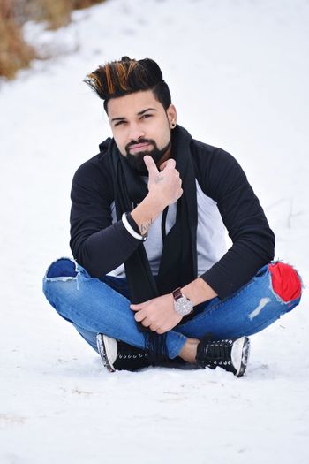 Young man sitting on snow covered land