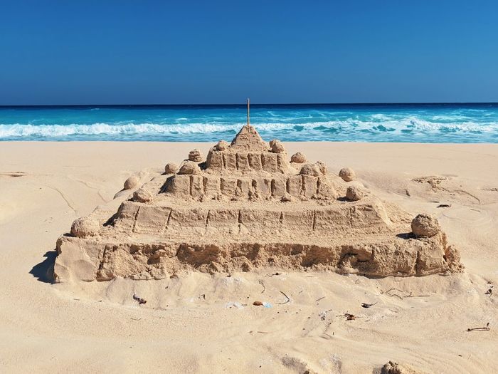 Sand castle at the beach against blue sky