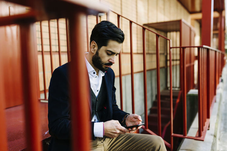 Businessman using mobile phone while sitting on steps
