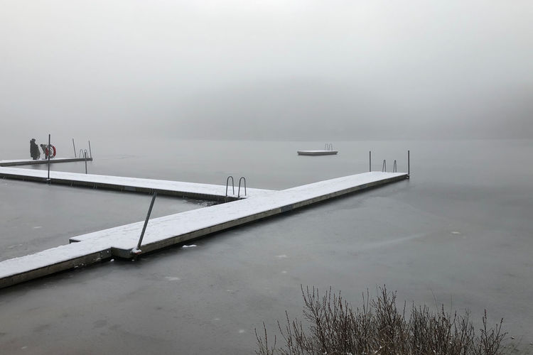Pier over lake against sky during winter
